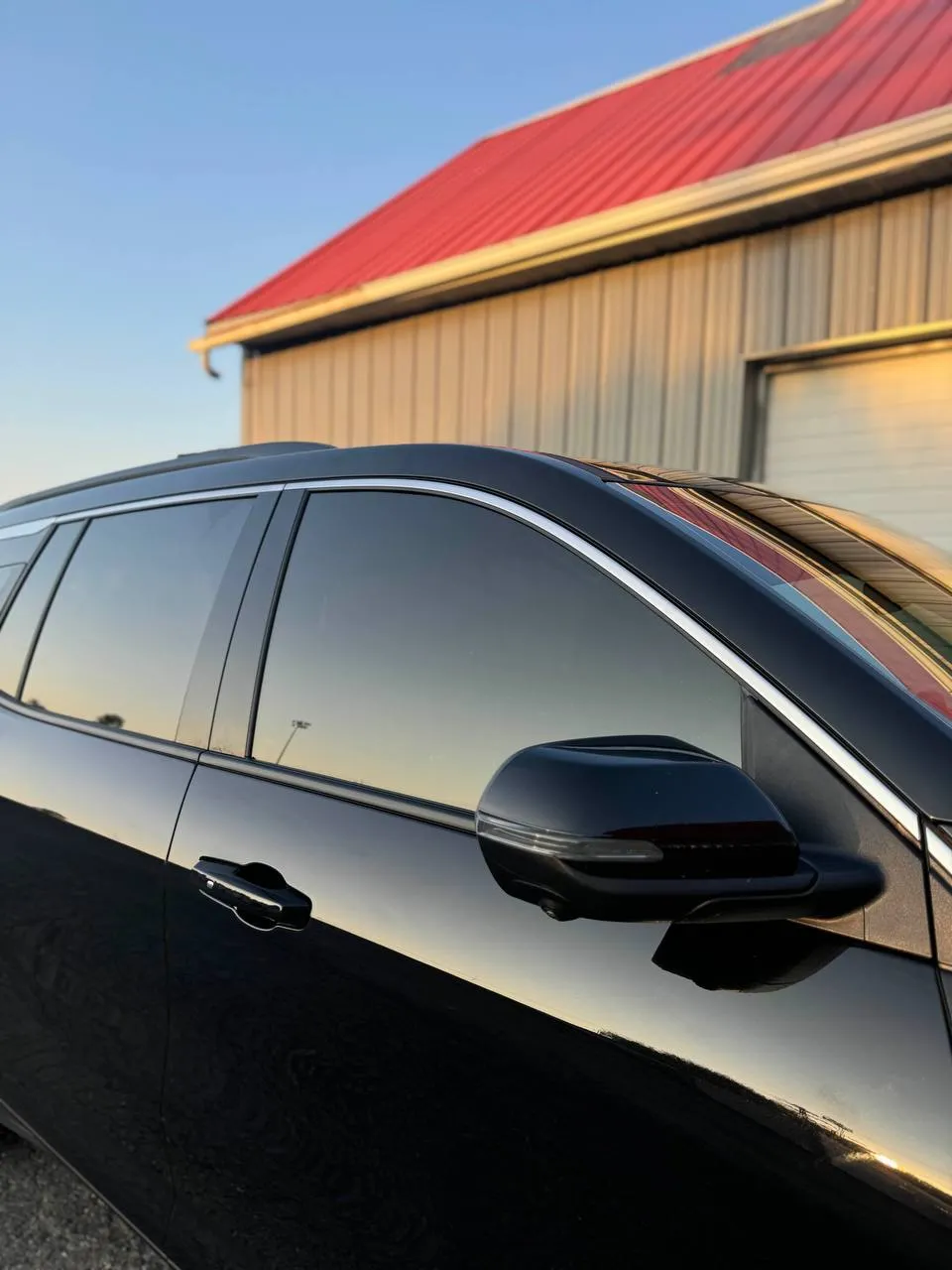 Black sedan with ceramic window tint at sunset