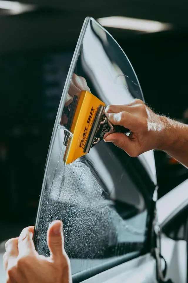 Technician applying window tint film to a side window